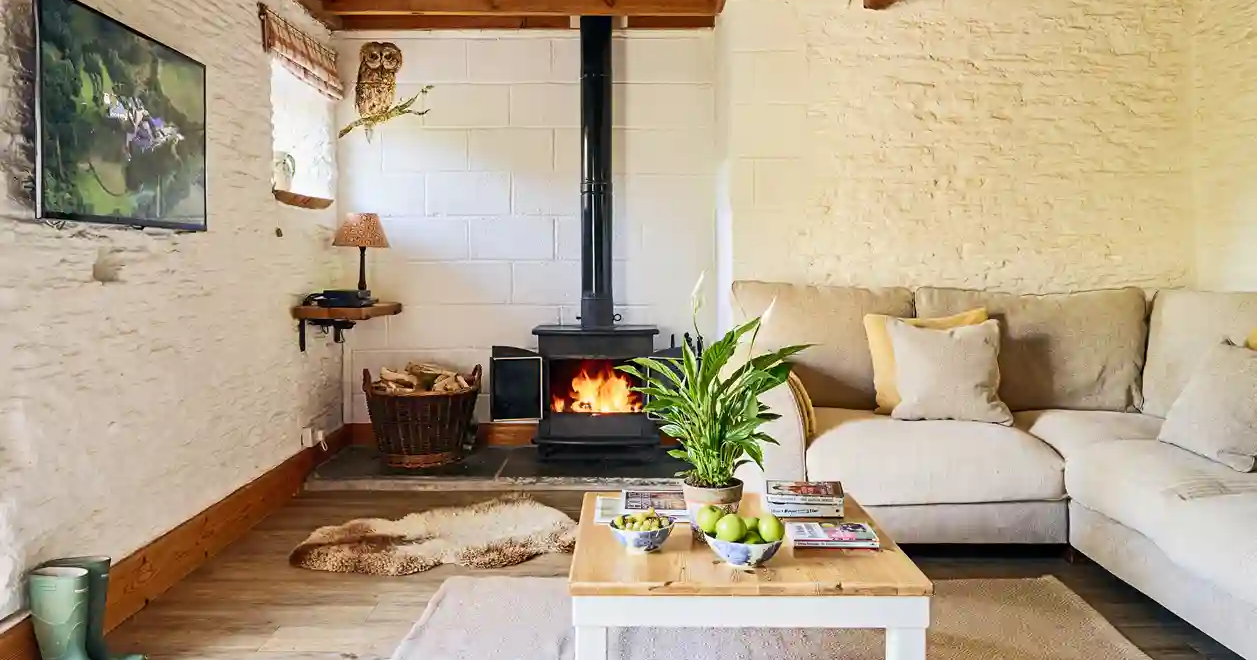 Cosy living room in Quarry at Flear Farm Cottages with log burner, neutral corner sofa, and rustic beams, creating a warm and inviting space.