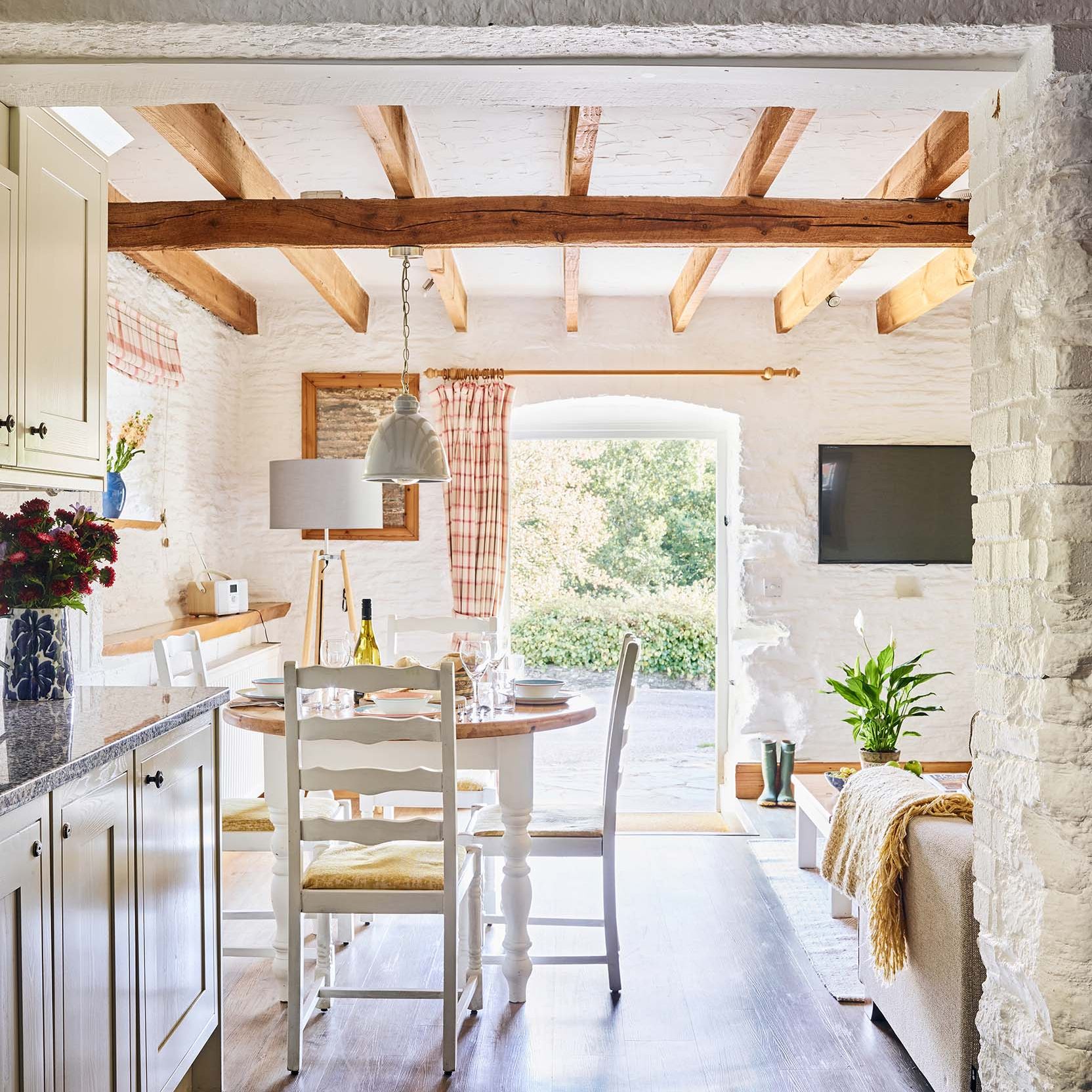 Bright view from Quarry’s kitchen into the dining and living area at Flear Farm Cottages, with beams, patio doors, and garden beyond.