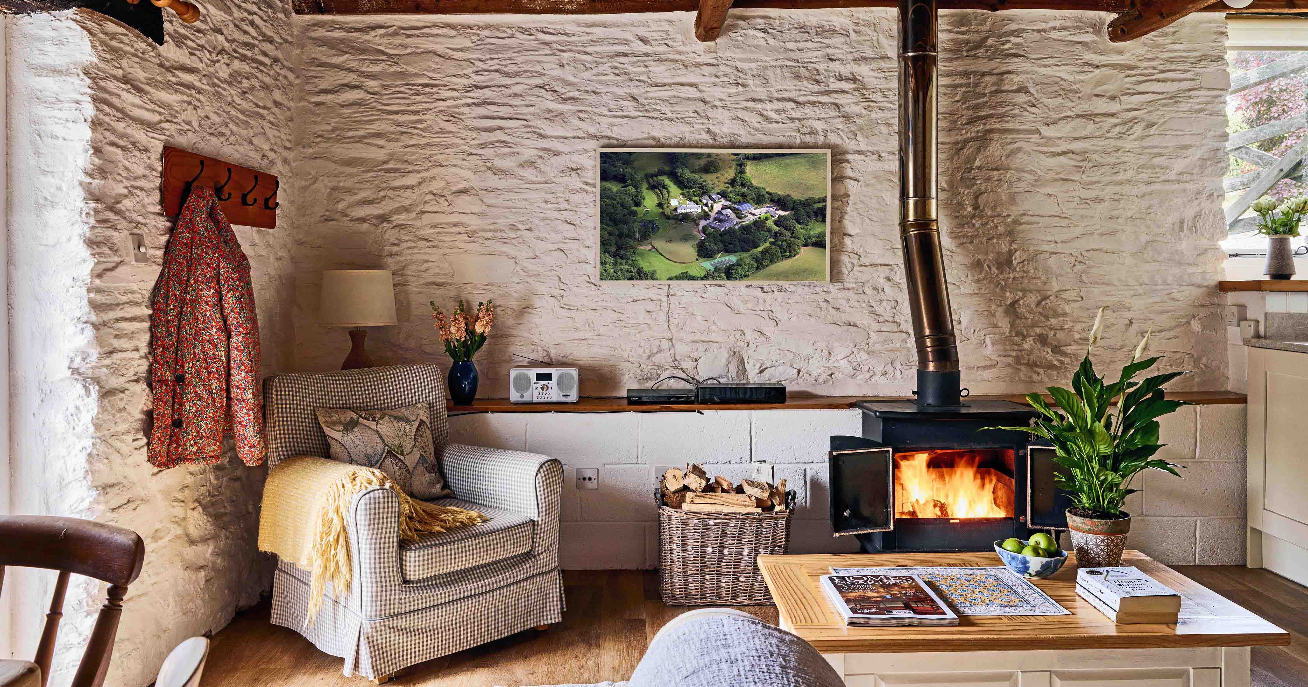 Cosy lounge in 1843 at Flear Farm Cottages, featuring a log burner, armchair, exposed beams, and warm rustic decor with countryside charm.