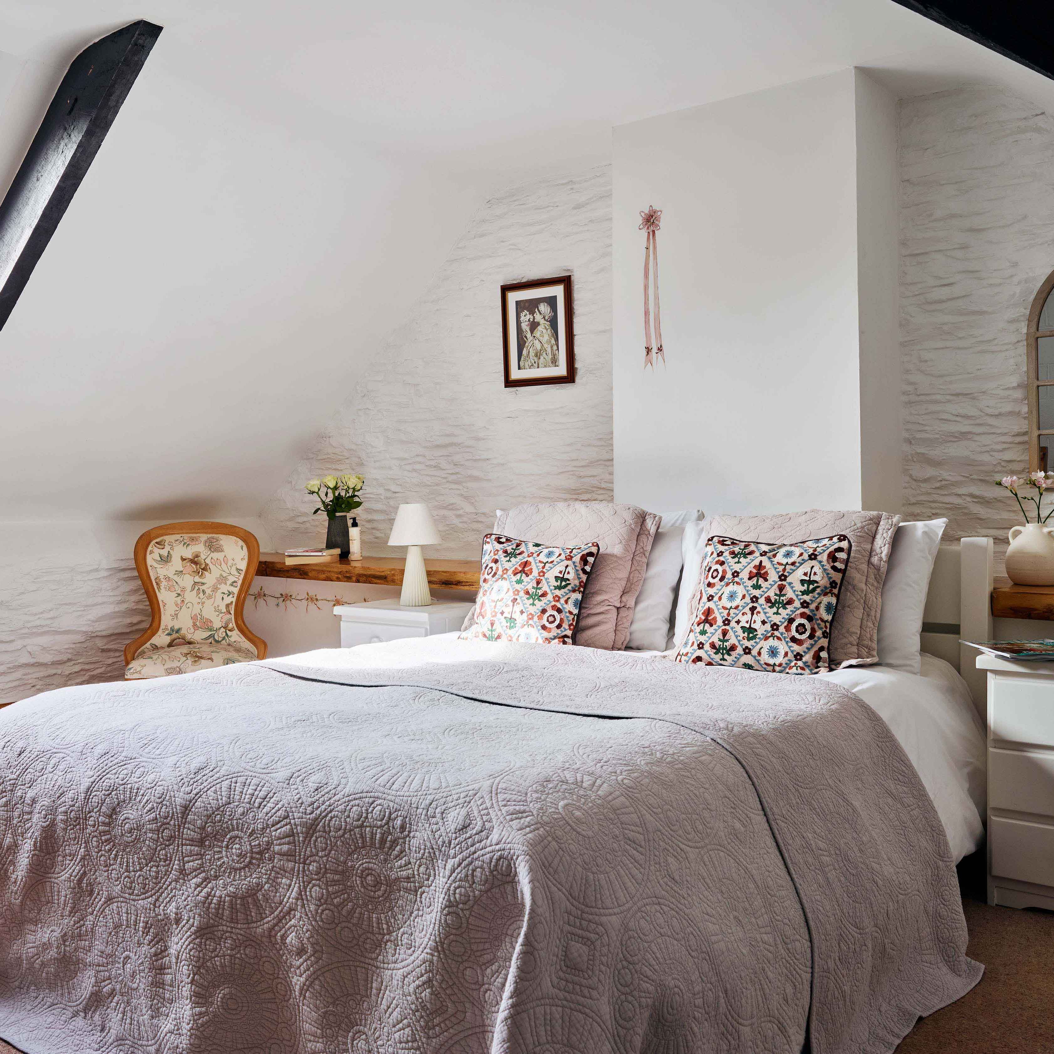 Master bedroom in 1843 at Flear Farm Cottages with a skylight, decorative cushions, soft grey bedding, and vintage-style furniture.