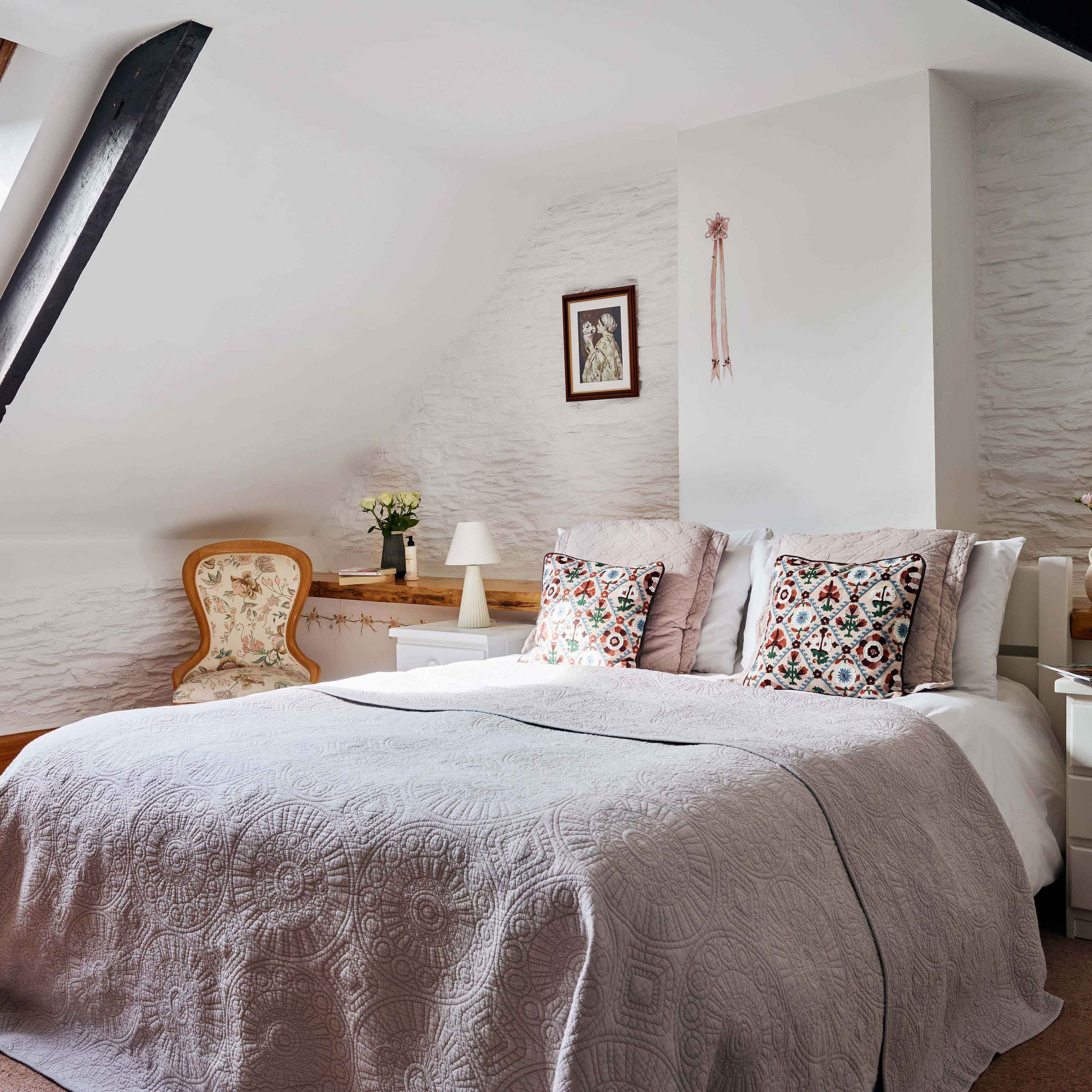Master bedroom in 1843 at Flear Farm Cottages with a skylight, decorative cushions, soft grey bedding, and vintage-style furniture.
