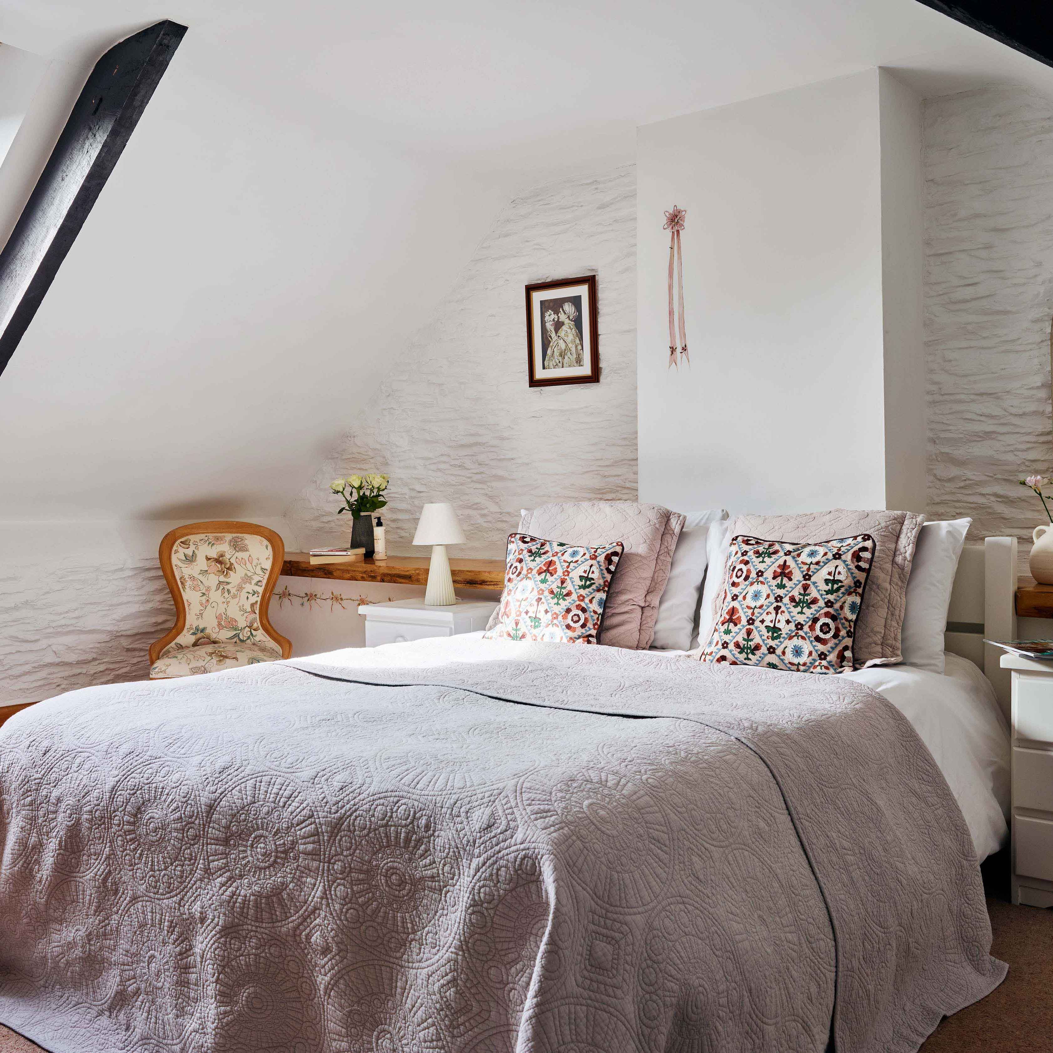Master bedroom in 1843 at Flear Farm Cottages with a skylight, decorative cushions, soft grey bedding, and vintage-style furniture.