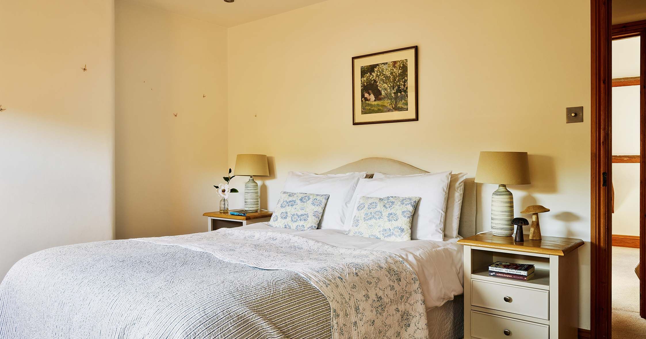 Master bedroom in Cartwheel at Flear Farm Cottages, featuring soft floral bedding, matching bedside tables, warm lighting, and a peaceful tone.