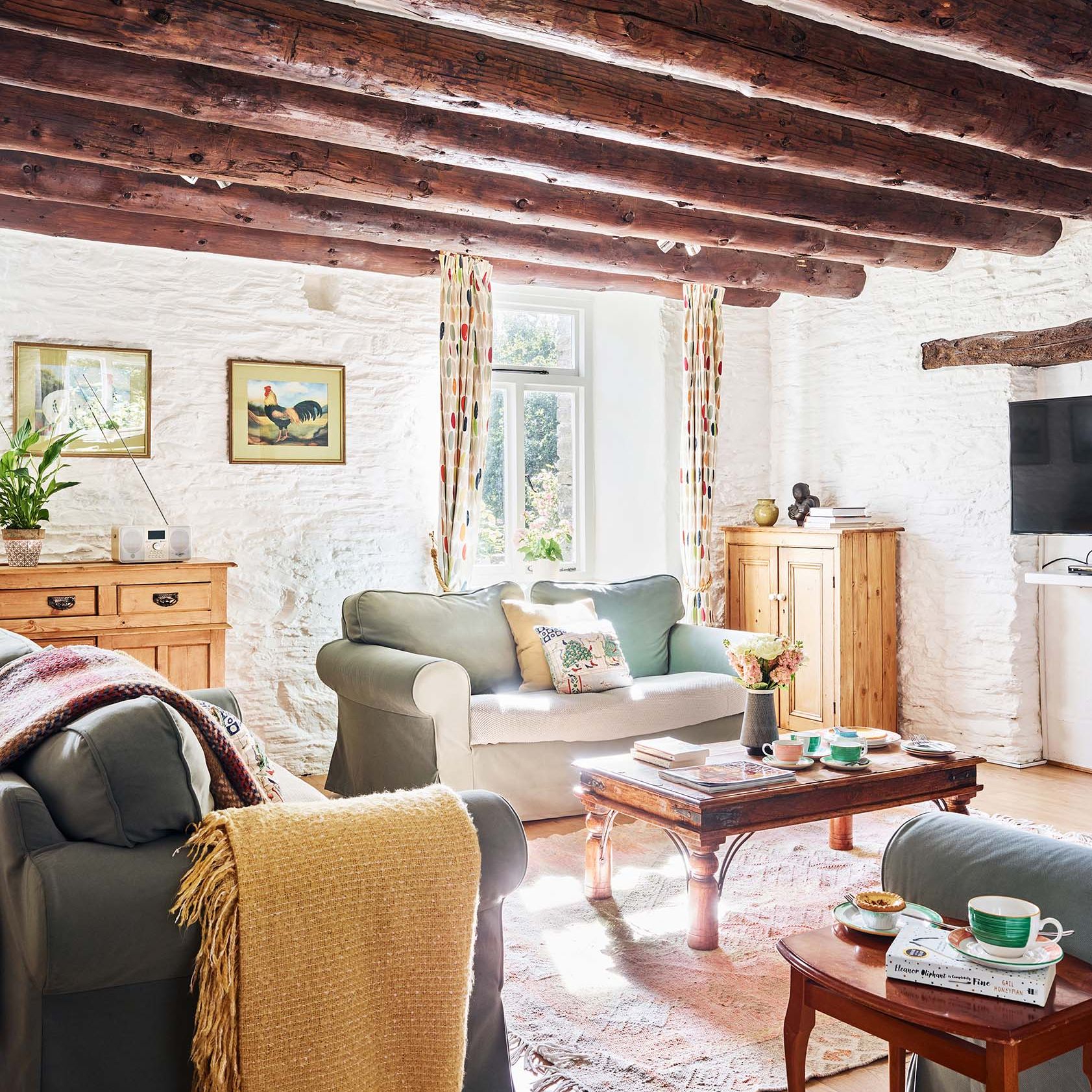 Portrait view of the Granary’s living room at Flear Farm Cottages, with exposed beams, soft seating, rustic furnishings, and sunlight streaming in.