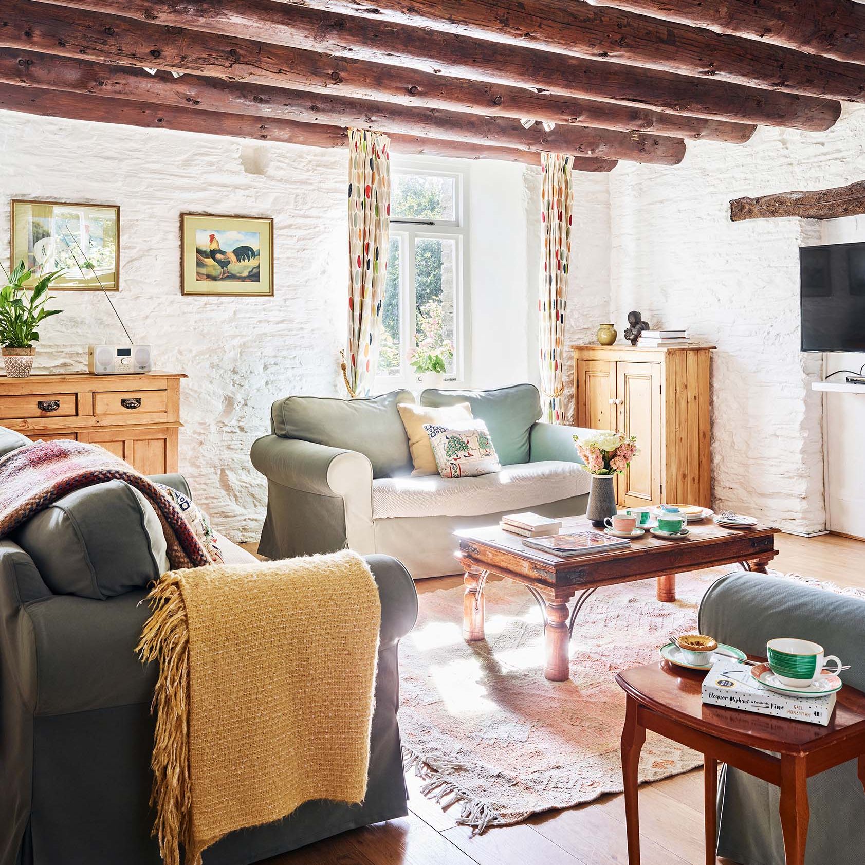 Portrait view of the Granary’s living room at Flear Farm Cottages, with exposed beams, soft seating, rustic furnishings, and sunlight streaming in.