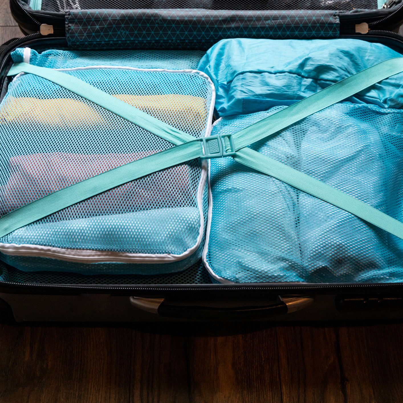 Suitcase packed with blue packing cubes and crossed straps