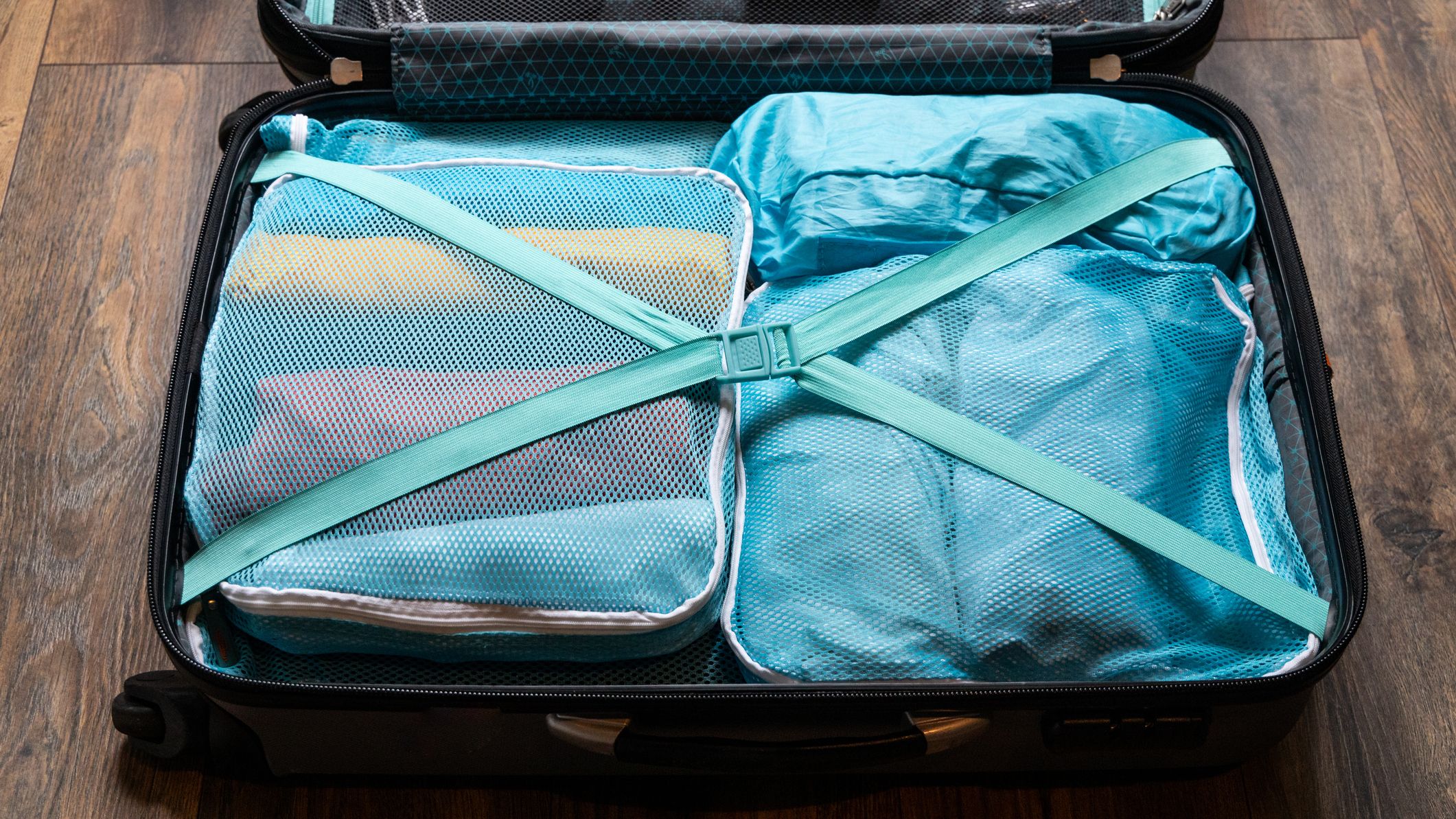 Suitcase packed with blue packing cubes and crossed straps