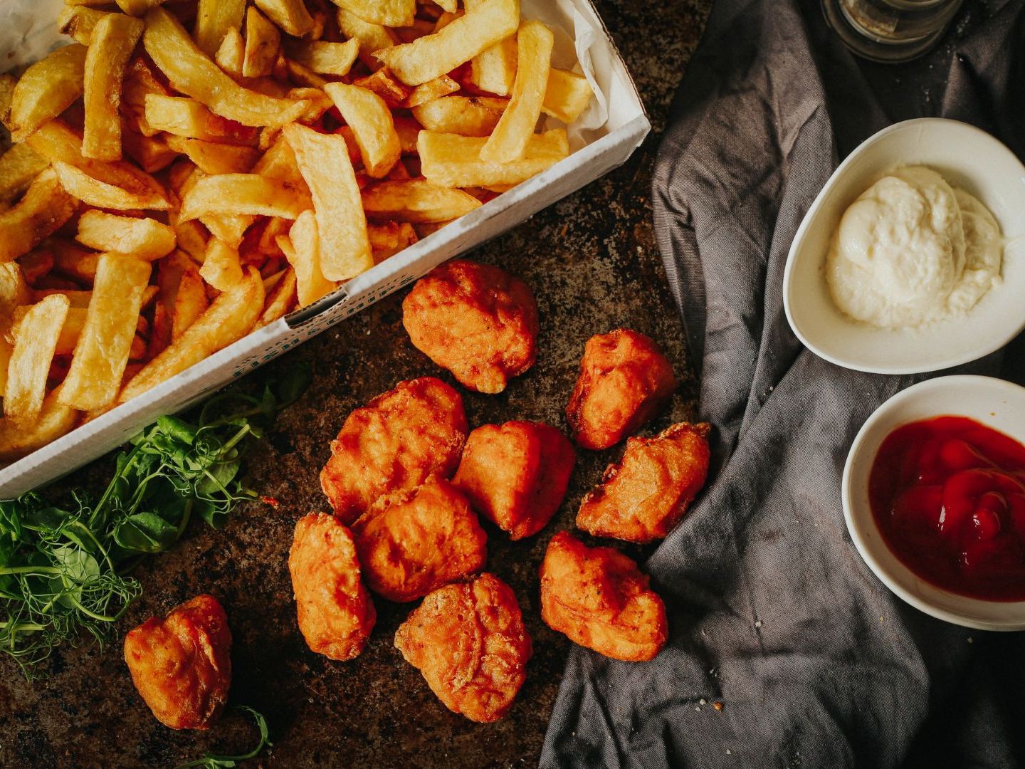 A serving of chicken nuggets and thick-cut fries with ketchup and mayonnaise dips.