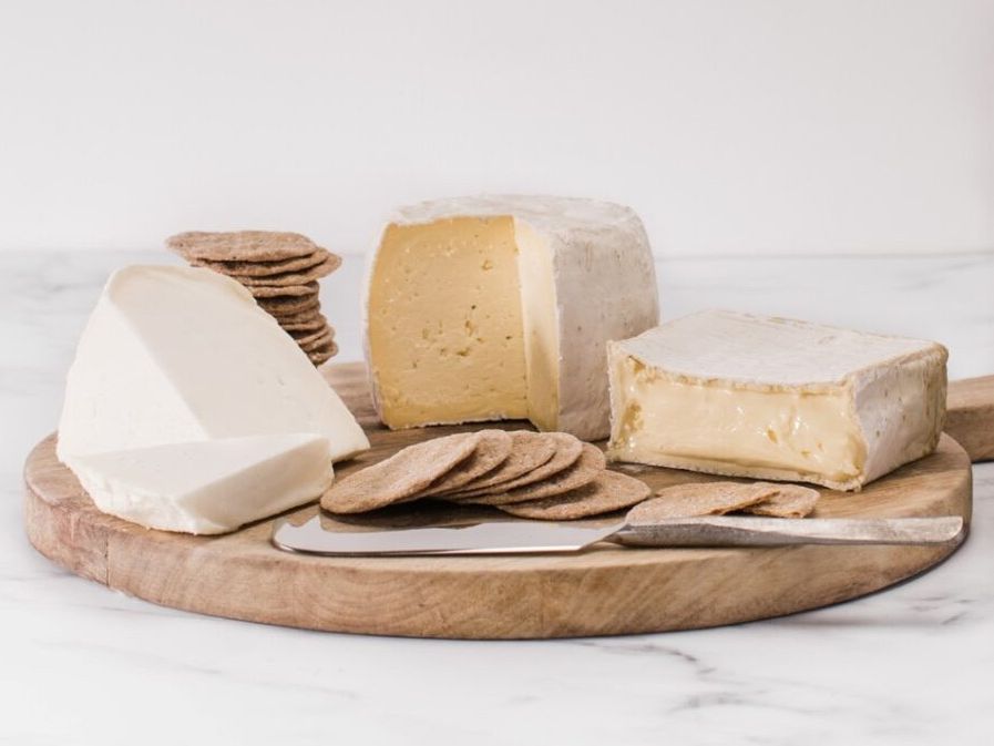 Assorted cheeses and crackers on a wooden board with a cheese knife