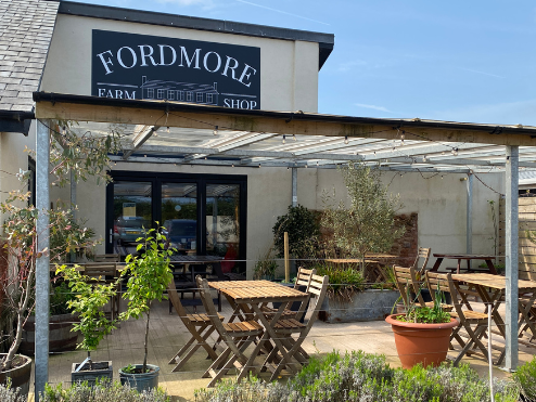 Outdoor seating area at Fordmore Farm Shop with wooden tables and pergola