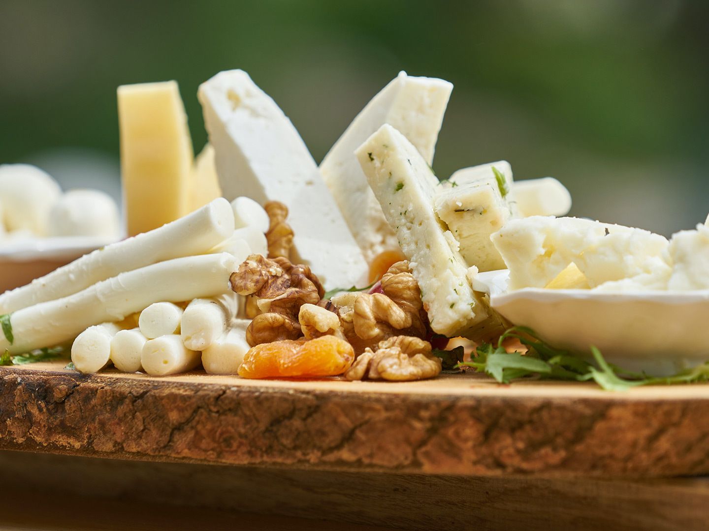 Assorted cheeses with walnuts and dried apricot on a wooden board
