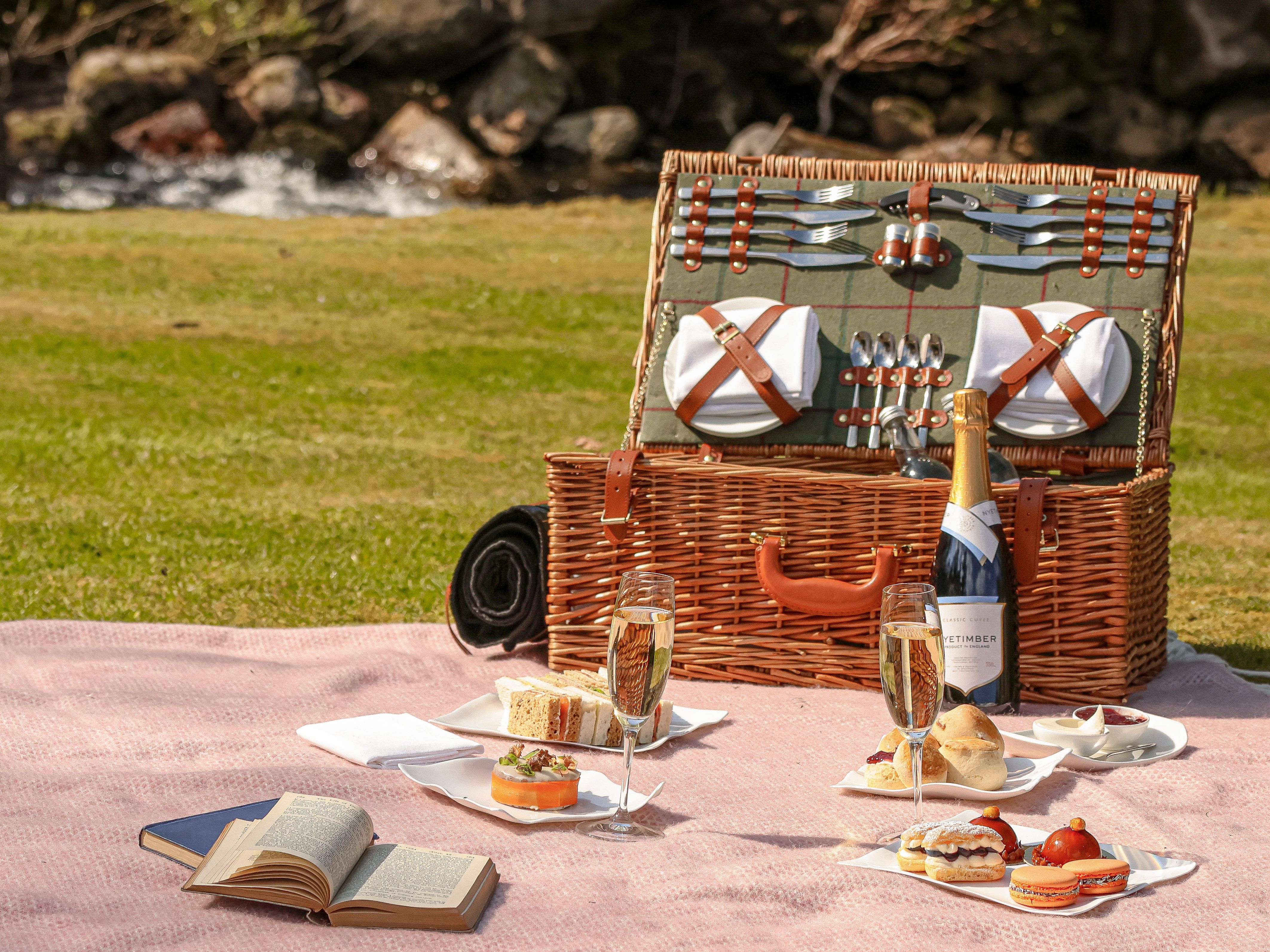 Gidleigh Park Afternoon Tea Picnic A wicker hamper, picnic blanket and treat are spread out on a lawn