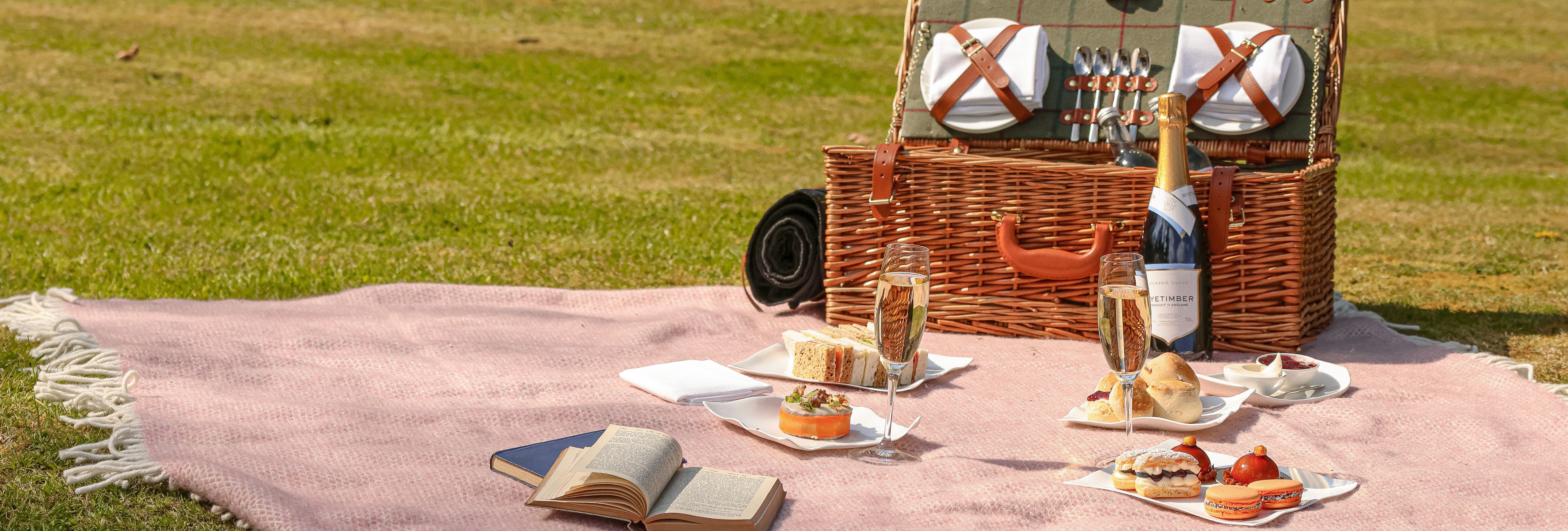 Gidleigh Park Afternoon Tea Picnic A wicker hamper, picnic blanket and treat are spread out on a lawn