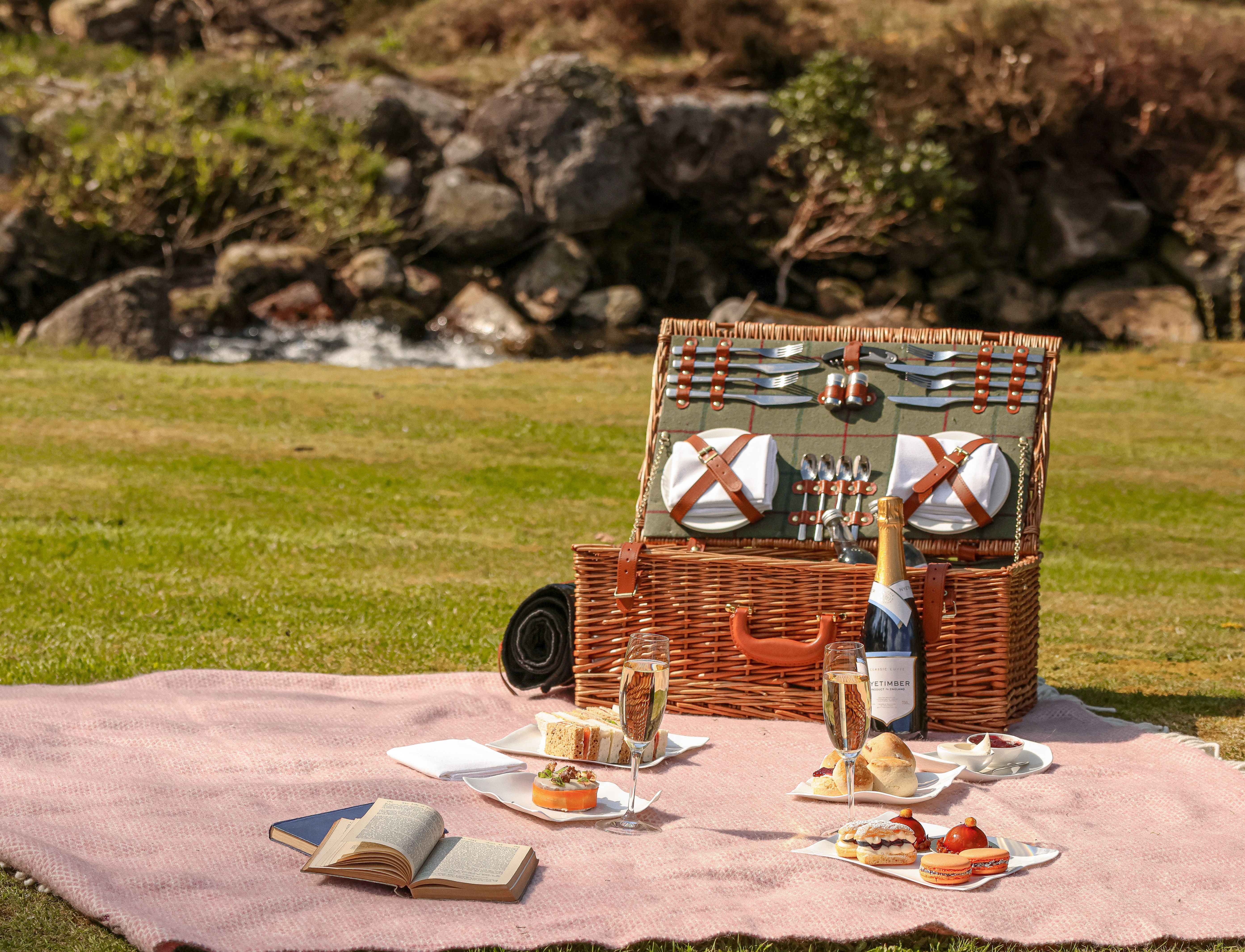Gidleigh Park Afternoon Tea Picnic A wicker hamper, picnic blanket and treat are spread out on a lawn