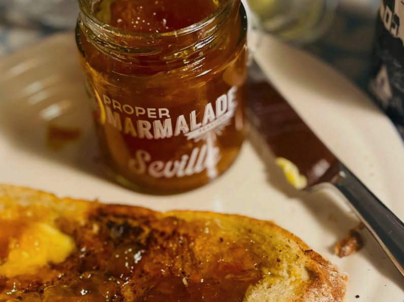 Proper Marmalade Co open jar next to a piece of toast spread with butter and marmalade with a knife