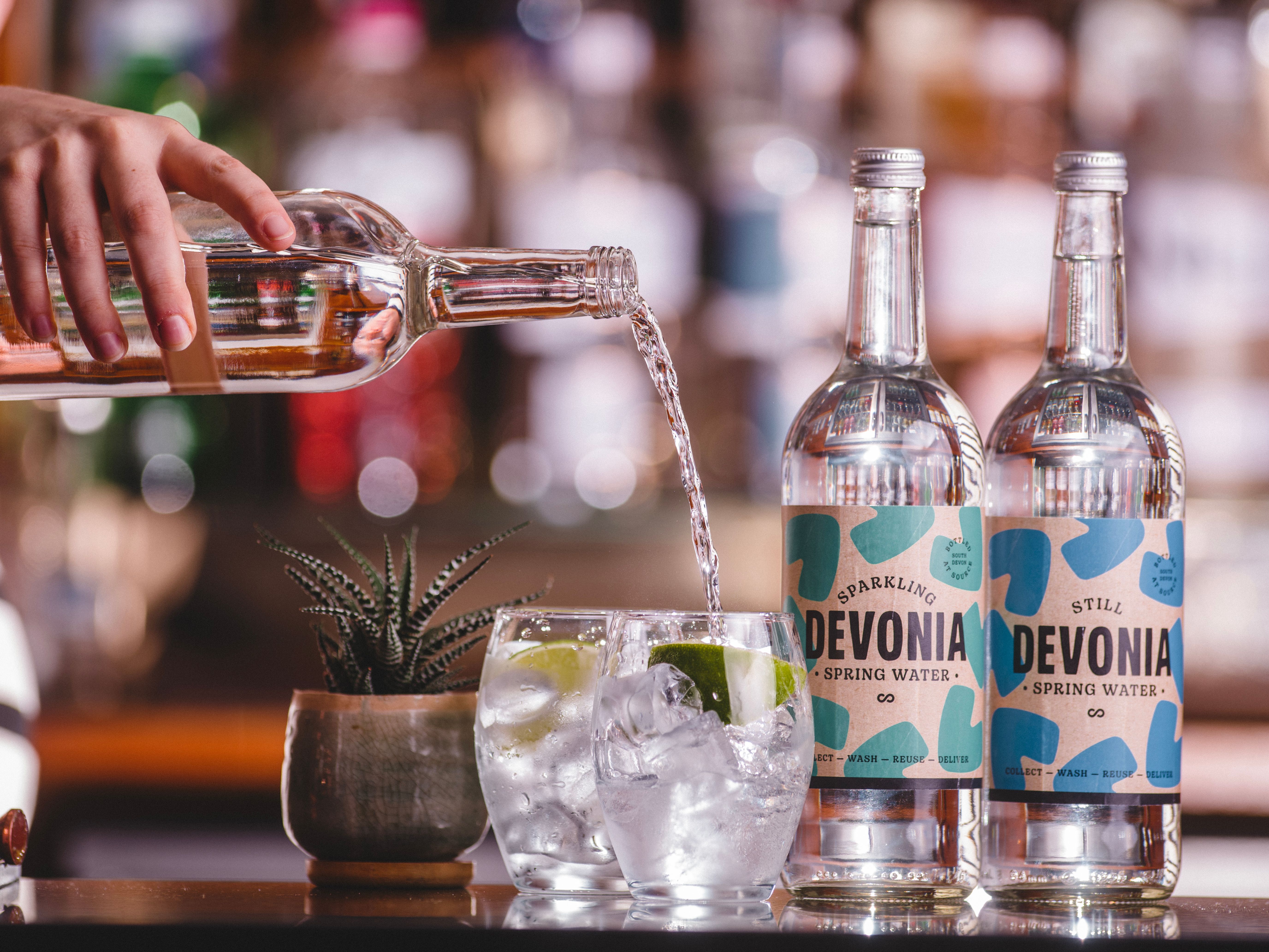 Two bottles of Devonia Spring Water and one being poured into a glass full of ice