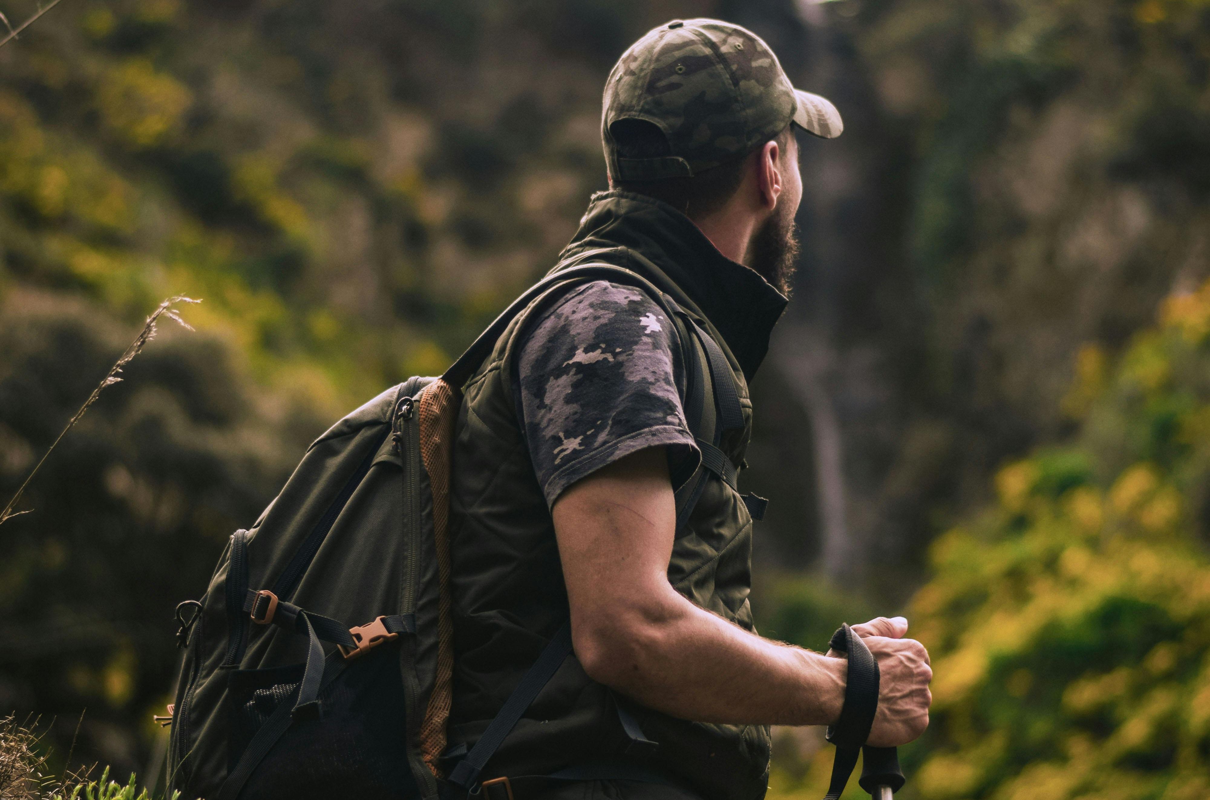 Man hiking through a lush, green mountain trail with a backpack and walking stick—great for Father’s Day activity ideas in nature.