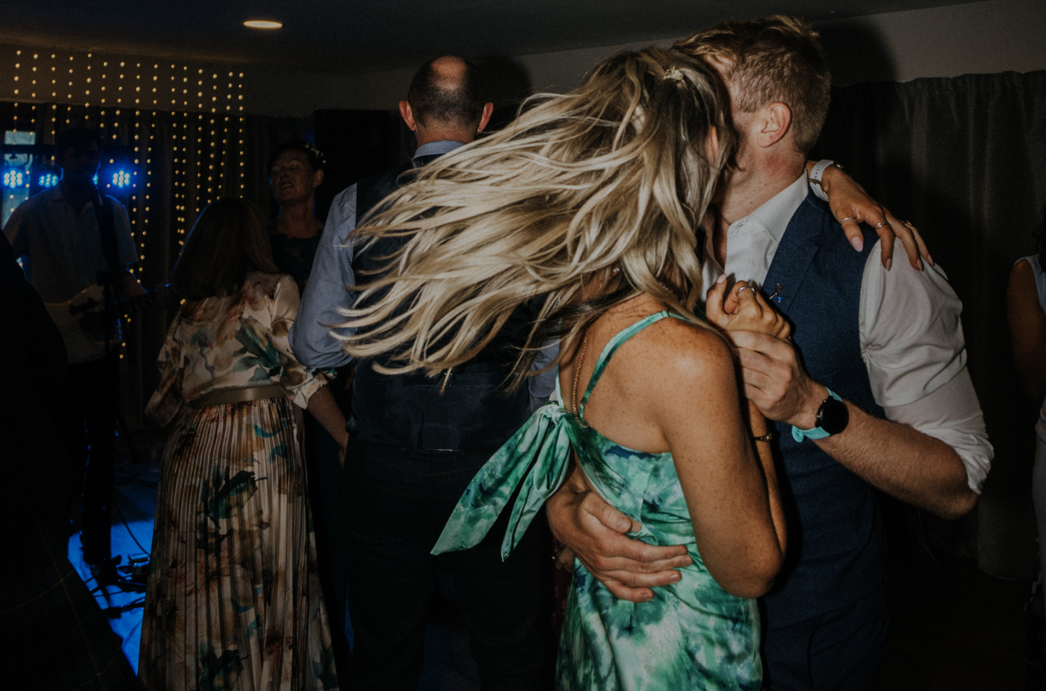A couple dancing on the dancefloor, the woman's hair is bouncing as she spins around.