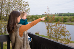 Woman holding child on balcony with views over fishing pond