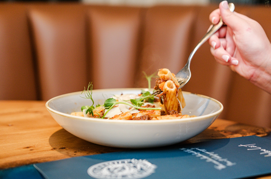 Person eating pasta dish