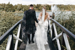 Bride and groom on bridge by fishing pond