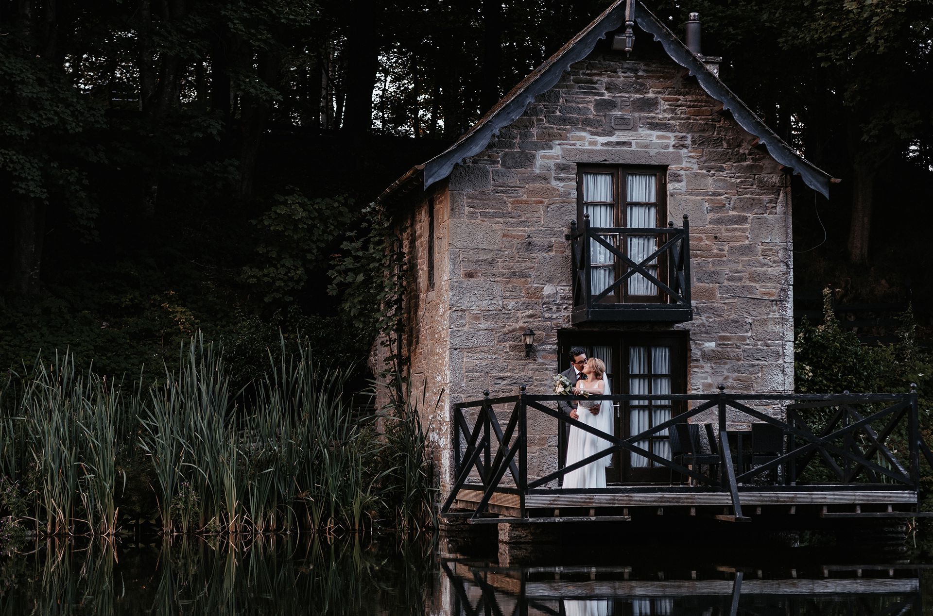 Bride and groom on boathouse balcony