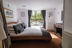Bed in room with views across fishing pond from open window