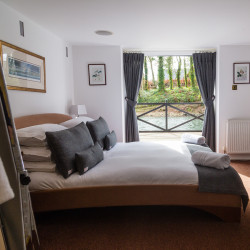 Bed in room with views across fishing pond from open window