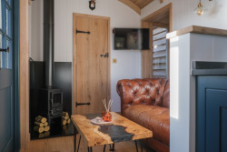 Log burner in seating area in shepherds hut