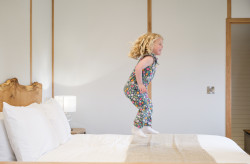 Child jumping on bed in The Burrow