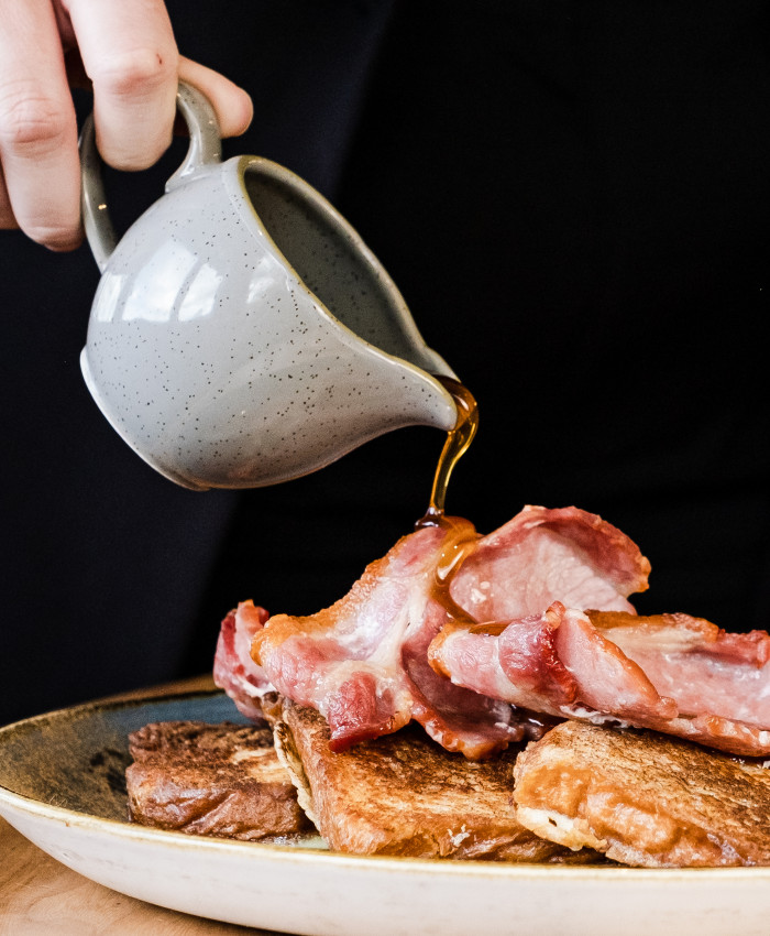 Maple syrup pouring over bacon and pancakes