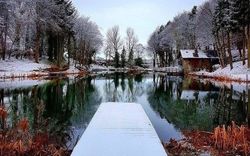 A frosty scene with views from a snow covered fishing pontoon out towards a fishing pond with the Leannan Boathouse.