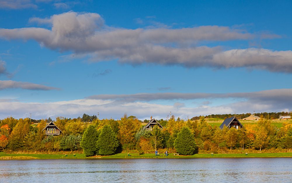 Three lodges hidden in the trees with views of the lochan in Autumn.