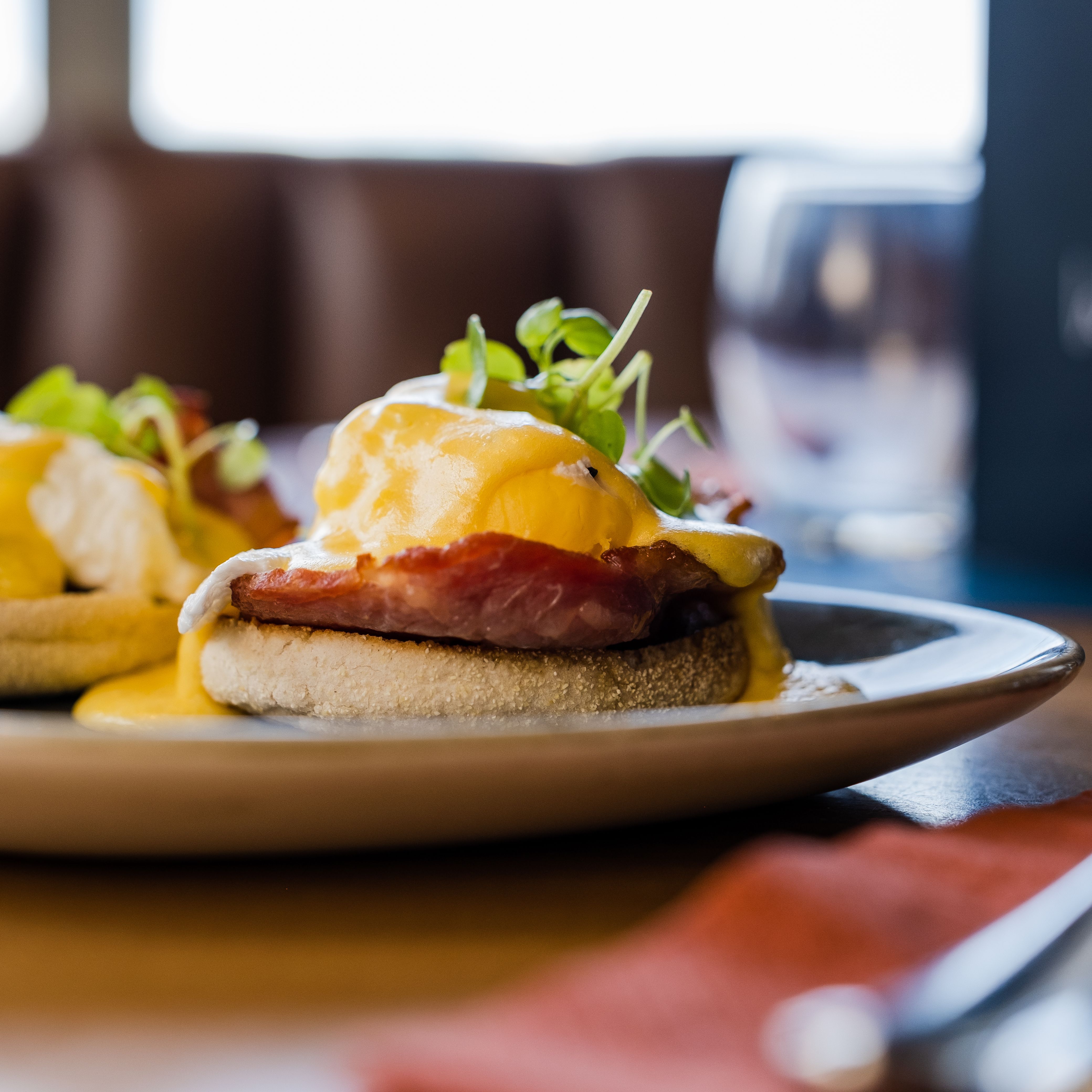 Eggs Benedict. A hollandaise sauce dripping over poached eggs with bacon on a toasted muffin.