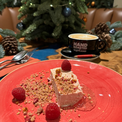 A traditional Scottish cranachan paired with a coffee and a festive backdrop of pine cones and twinkling lights.