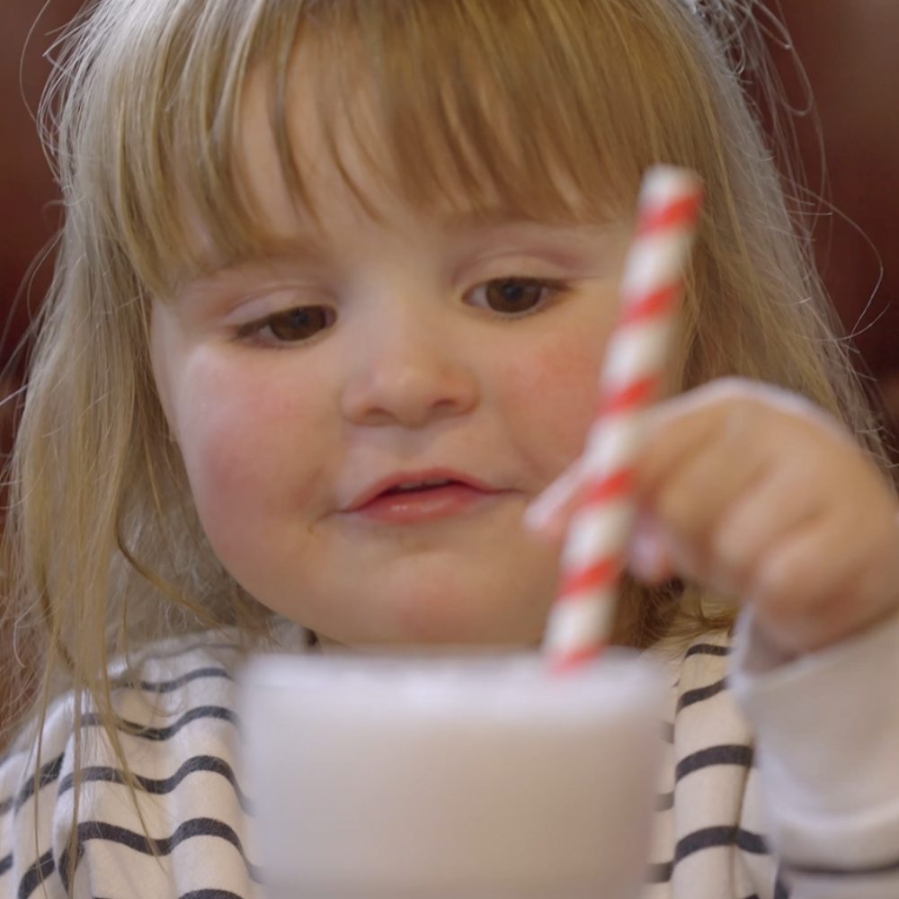 A cute child tucking into a milkshake.