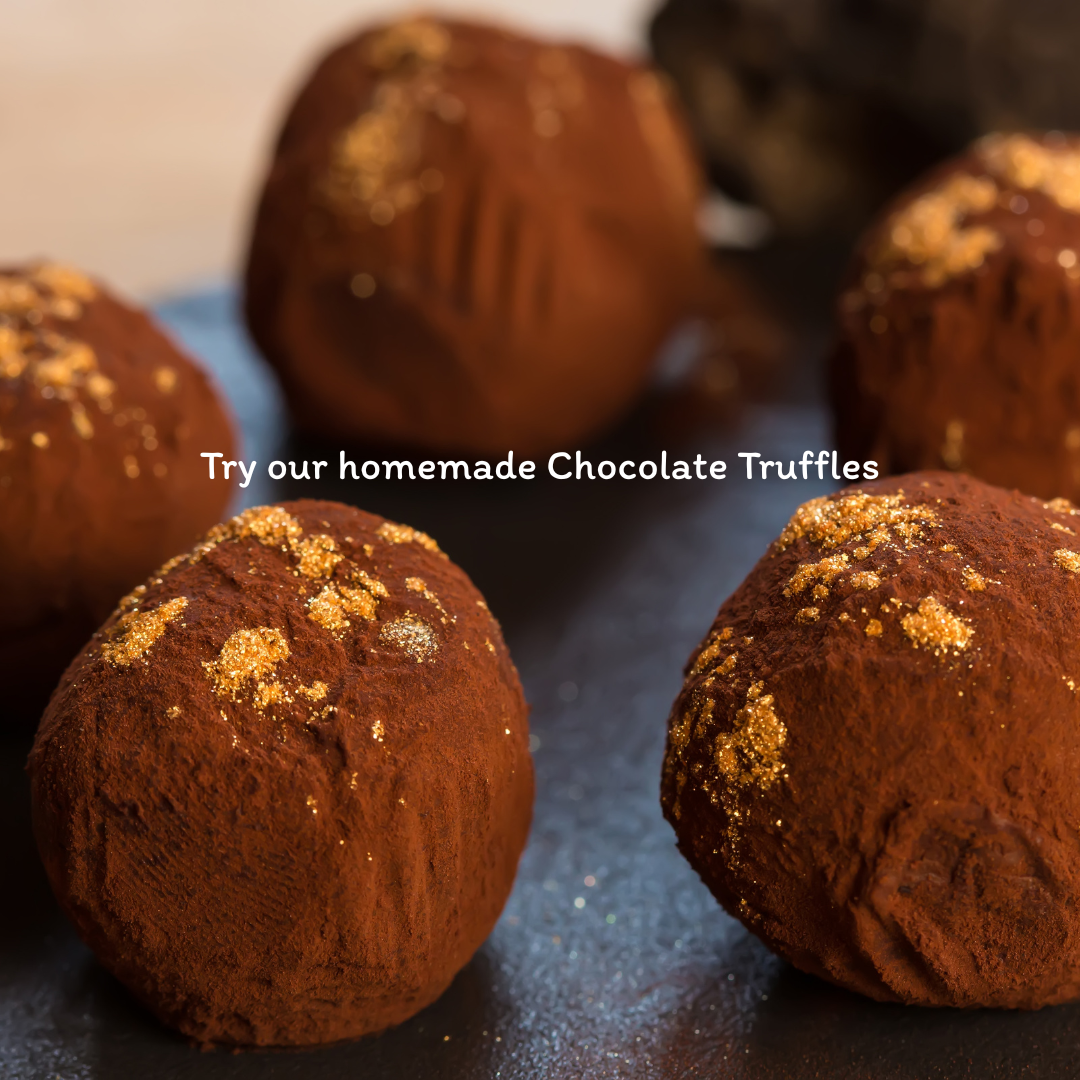 Homemade chocolate truffles topped with gold dust on a dark surface