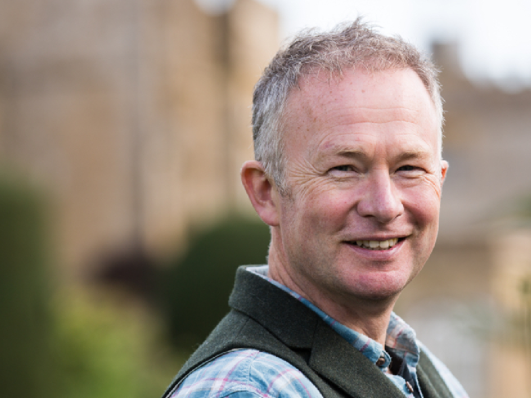 Smiling middle-aged man in plaid shirt and vest standing outdoors