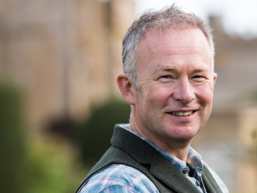 Smiling middle-aged man in plaid shirt and vest standing outdoors