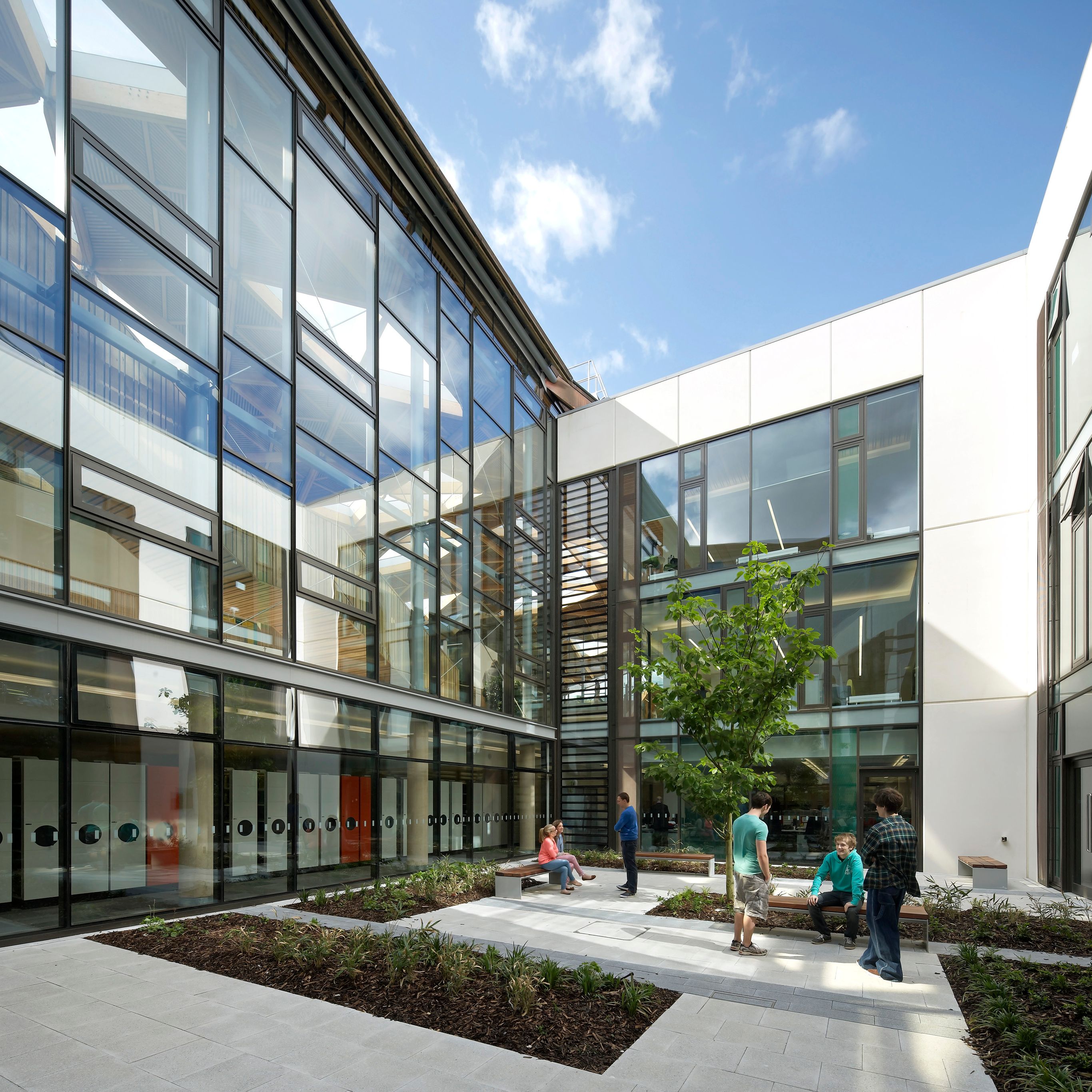 Modern building courtyard with glass walls and people talking and sitting on benches