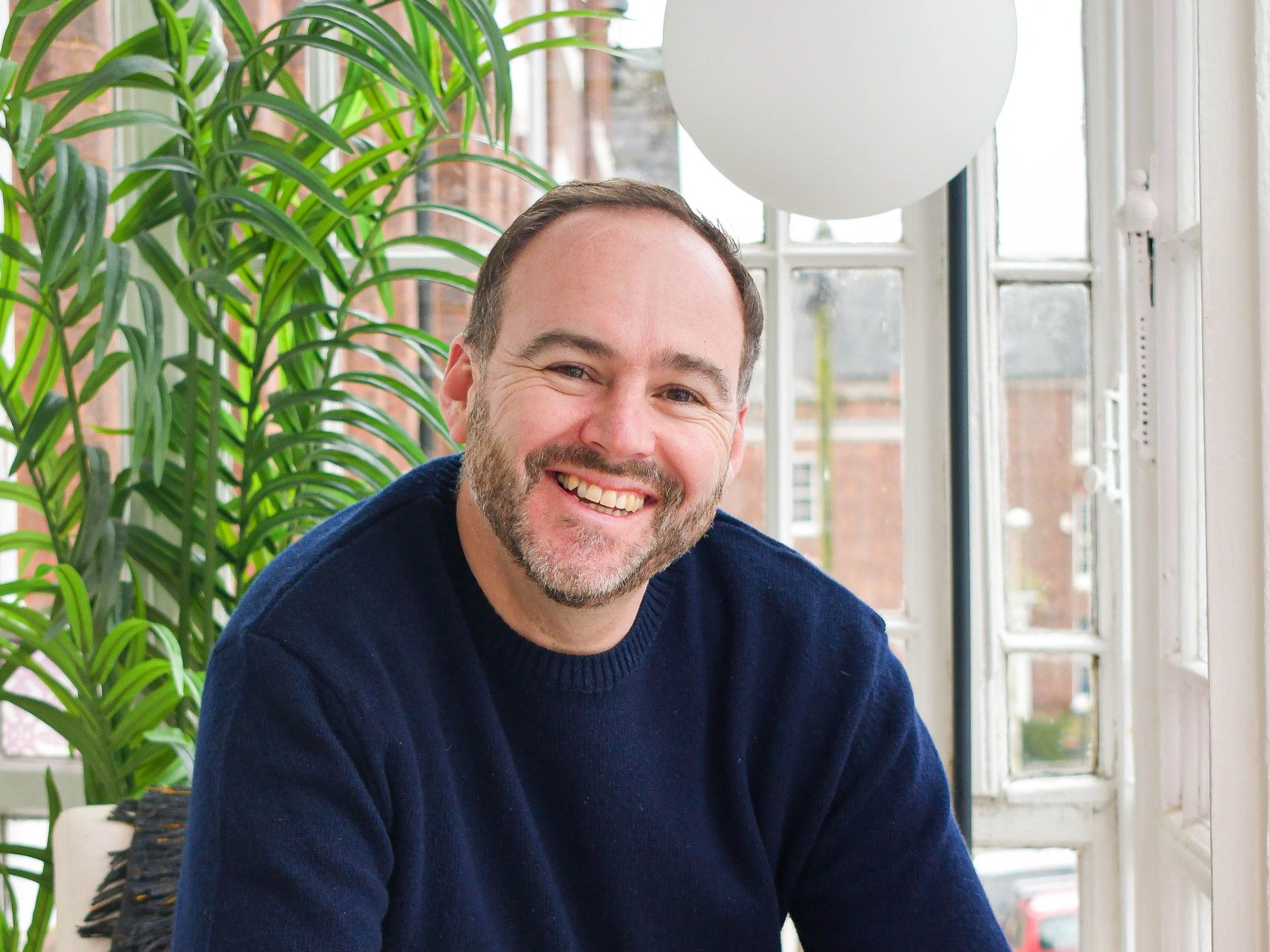 Smiling man sitting indoors holding a drink