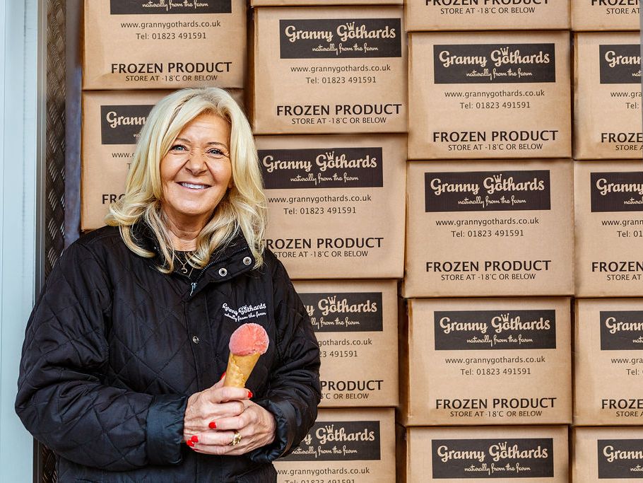 Woman holding an ice cream cone standing in front of stacked Granny Gothards frozen product boxes.