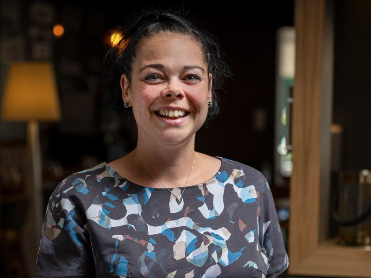 Smiling woman standing indoors with a patterned shirt