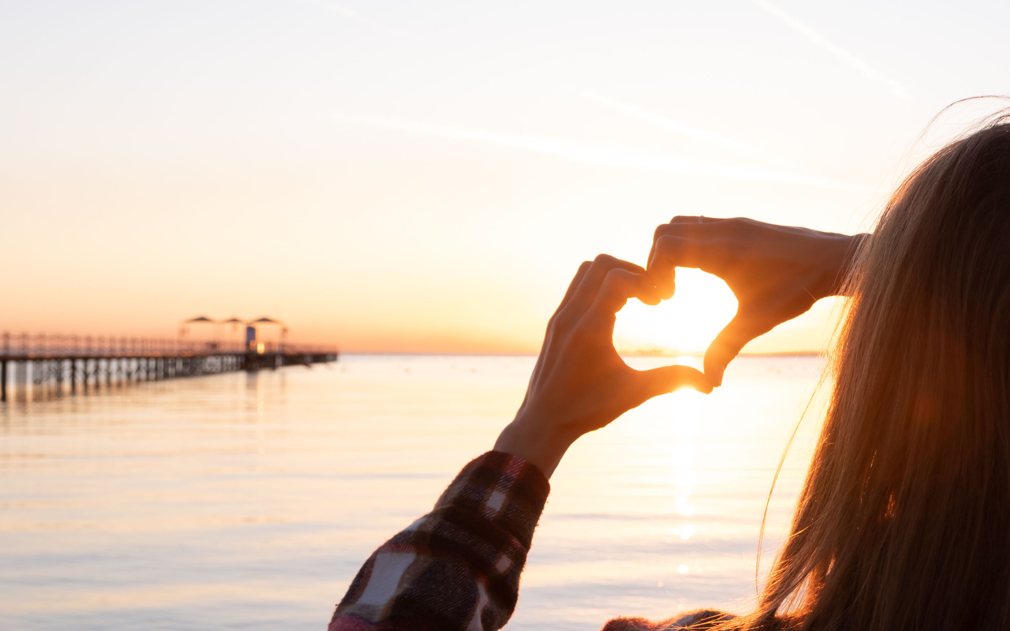 Woman with hands in heart position watching the sunset