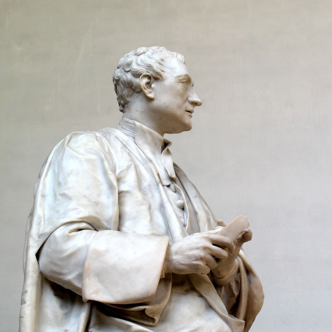 Marble statue of Sir Isaac Newton in academic robes, holding a book, shown in profile against a plain background.