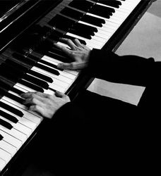 Person playing a grand piano with both hands on the keys