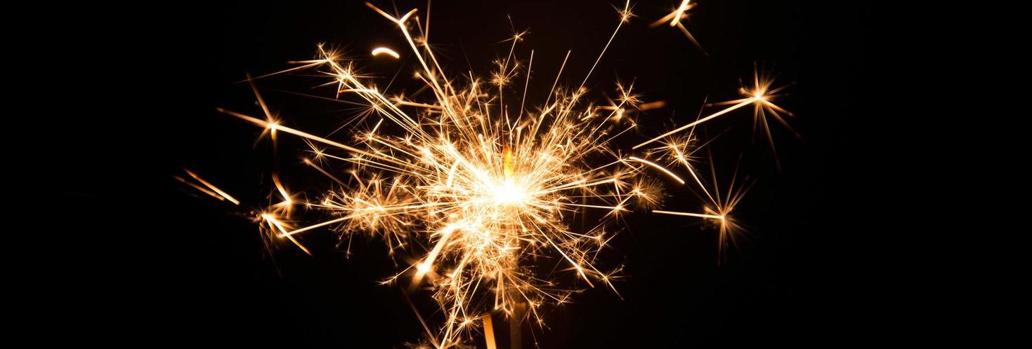 Brightly burning sparkler against a dark black background