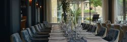 Elegant dining table set for a formal event in a stylish restaurant with velvet chairs and candles.