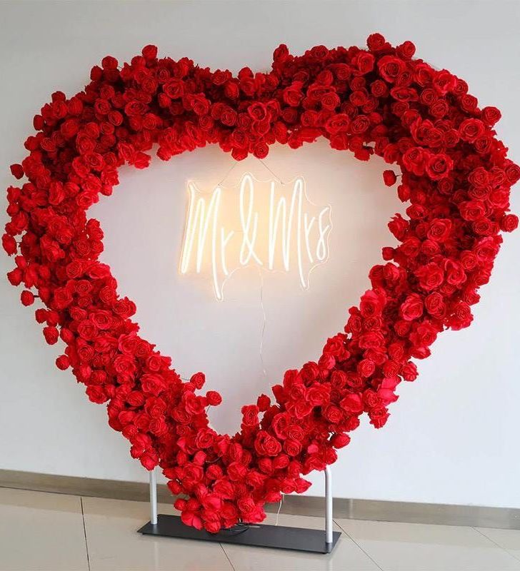 Large heart-shaped frame made of red roses with a 'Mr & Mrs' neon sign in the center