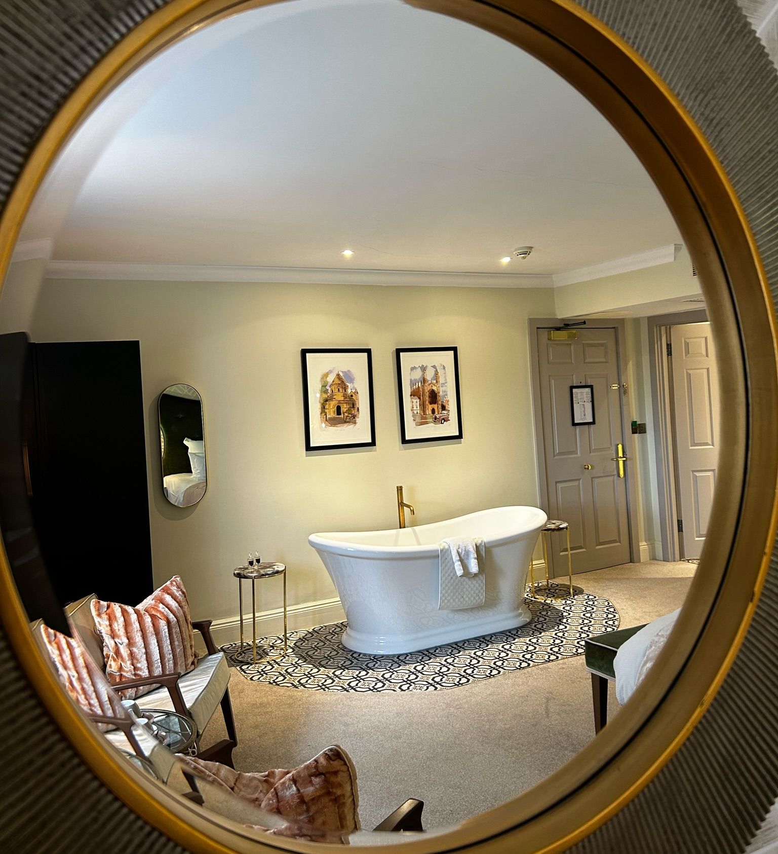 Reflection of a modern bathtub and stylish room through a round mirror